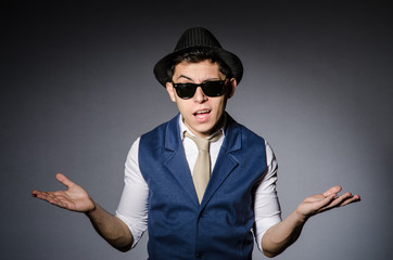 Young man in blue vest and hat against gray