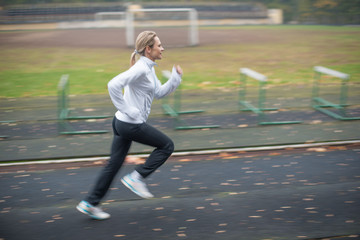 Woman running in the stadium (panning technique, small depth of field)