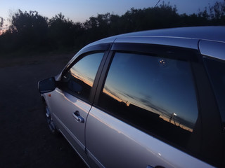 Fototapeta na wymiar Закат, отражающийся в стеклах автомобиля