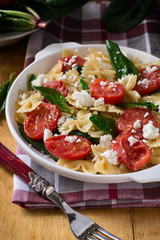Farfalle with Tomatoes, Spinach and Cheese in a plate on a wooden table