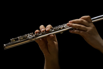 Hands of musician playing a flute in dark colors