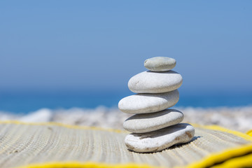 Pebble stones on the straw mat, near the sea, on the beach.

