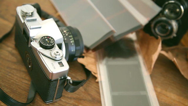 still life of two old retro vintage film cameras with its negatives, on the table