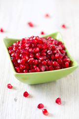 pomegranate seeds in a bowl on wooden surface