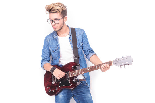 young casual guitarist playing his electric guitar and looks awa