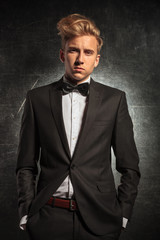 man posing in studio wearing tuxedo with hands in pockets