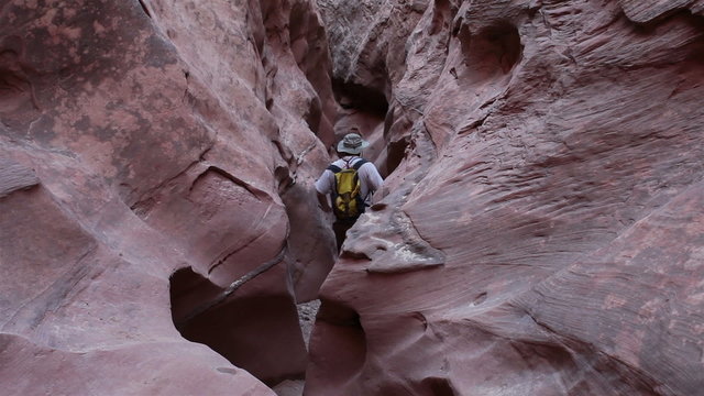 Man climbs hikes out narrow desert slot canyon HD 1593