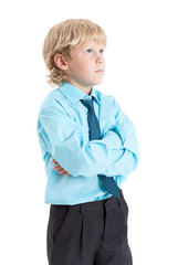 Young blond boy in blue shirt and tie standing with clasped hands, isolated on white background