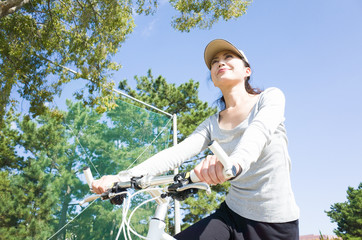 青空をバックにして自転車に乗っている日本人女性
