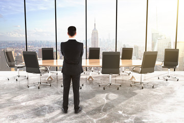 Businessman in conference room with big round table and chairs i
