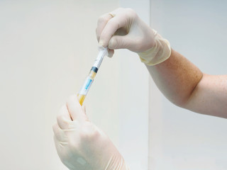Hands holding separated blood and syringe in test tube at  laboratory