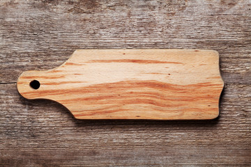 Empty beech cutting board with space for text on wood texture background, top view