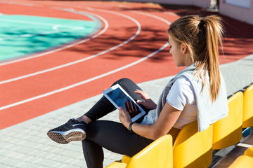 Woman resting with tablet computer at stadium