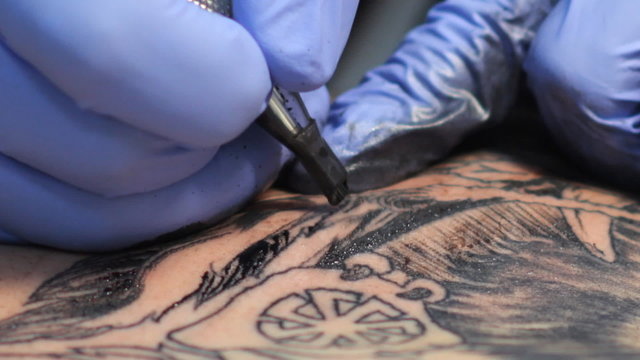 Tattoo master make tattoo a man in the tattoo parlor