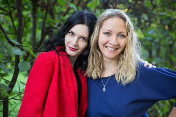 Two smiling woman posing in green park