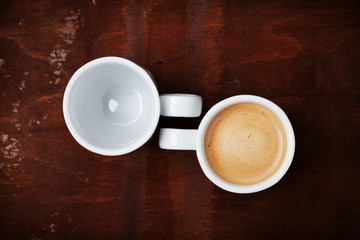 Empty and full cup of fresh coffee on rustic wooden table, benefits and harms of coffee concept, top view