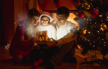 smiling family looking inside of glowing Christmas gift box