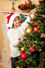 Fototapeta na wymiar happy smiling girl decorating Christmas tree