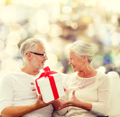 Obraz na płótnie Canvas happy senior couple with gift box at home