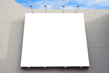 Blank poster board wall in modern shopping mall on a cloudy day.
