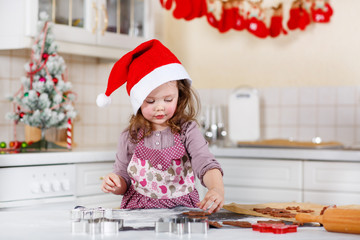 Little girl baking gingerbread cookies in domestic kitchen