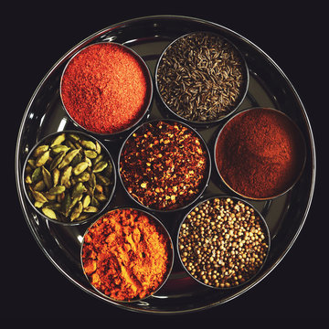 Rack with traditional indian spices for cooking - cardamom, turmeric, cumin, coriander seeds, cinnamon and chili