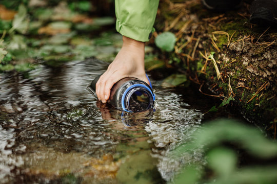 woman taking water from forest spring on hiking trip