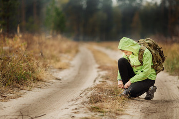 woman on a hiking trail ties the shoelace on her walking shoe