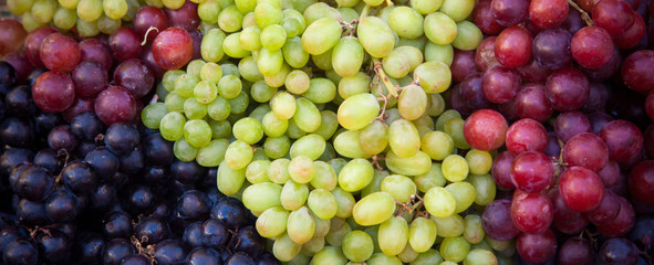 Various kinds of fresh grapes at market stall