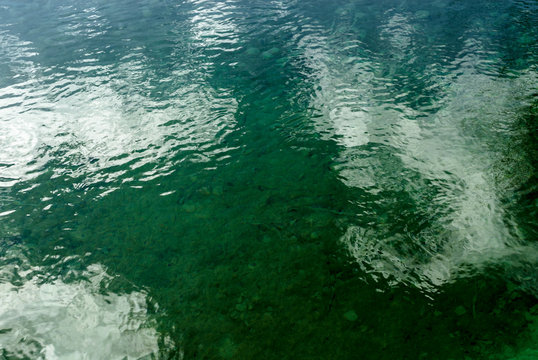 texture with the reflexes of the clouds on the green surface of the water