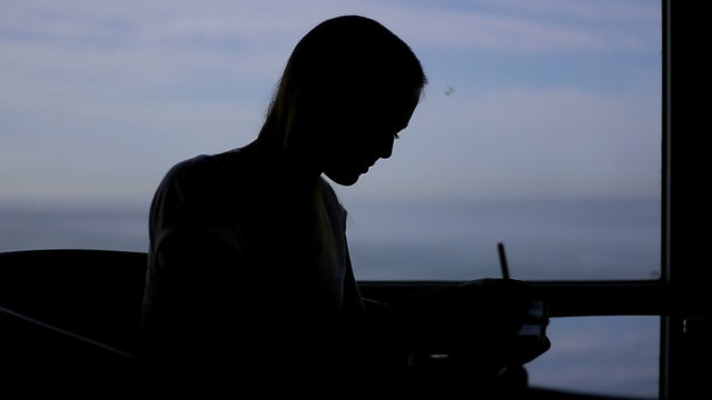 silhouette of young beautiful girl sits in a cafe with panoramic