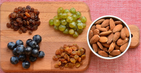 Various raisins, vine berries and almonds on chopping board