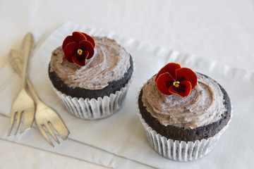 Homemade chocolate cupcakes with cookie and cream frosting and edible flower