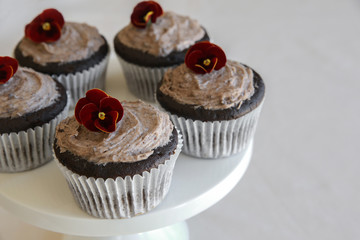 Homemade chocolate cupcakes with cookie and cream frosting and edible flower