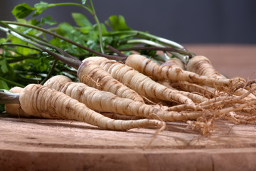 fresh parsley with roots on wooden cutting board