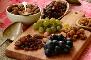 Various raisins, vine berries and almonds on chopping board