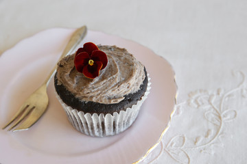 Homemade chocolate cupcakes with cookie and cream frosting and edible flower