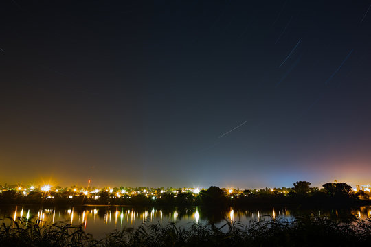 Star trail in the night sky on a background city lighting. 