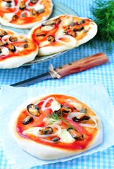 homemade mini pizza with mussels, calamari, onion, tomato, mozzarella and capers
