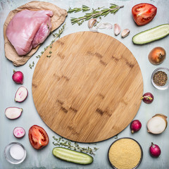 chicken breast on paper with seasoned autumn vegetables Around a round cutting board on rustic wooden background top view