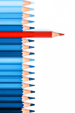 One red pencil among blue ones isolated on white background, standing out of the crowd concept