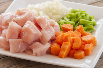 Raw chicken small pieces close up on wooden background