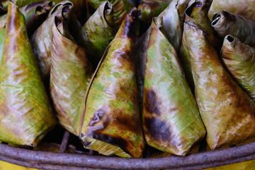 Sticky rice wrapped with banana leaf and banana grilling on stove