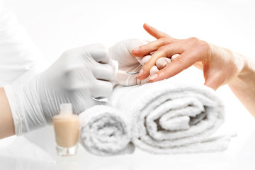 Malowanie paznokci. Dłonie kobiety podczas zabiegu manicure w salonie kosmetycznym