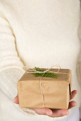 Mujer ofreciendo un regalo envuelto y decorado para celebrar la Navidad