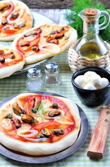 homemade mini pizza with mussels, calamari, onion, tomato, mozzarella and capers