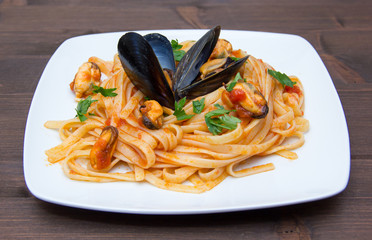 Pasta with mussels on the plate on wooden table