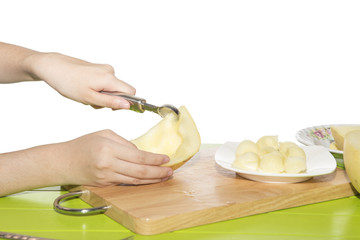 Cantaloupe is being made into balls on a white plate.