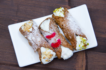Cannoli with ricotta cheese on wooden table seen from above