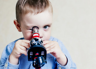 child looking in a microscope. little boy carefully studying something with microscope